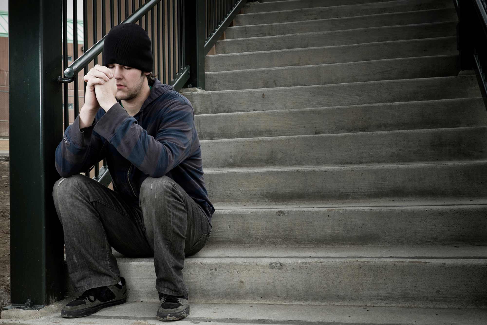 A man sits on concrete steps and prays