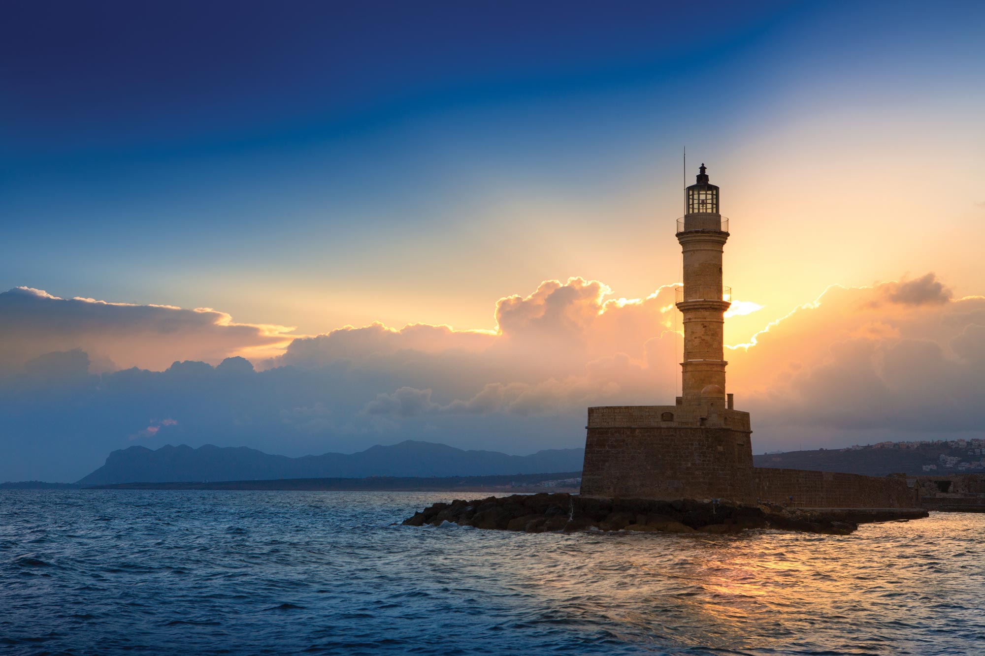 The sun rises behind a lighthouse