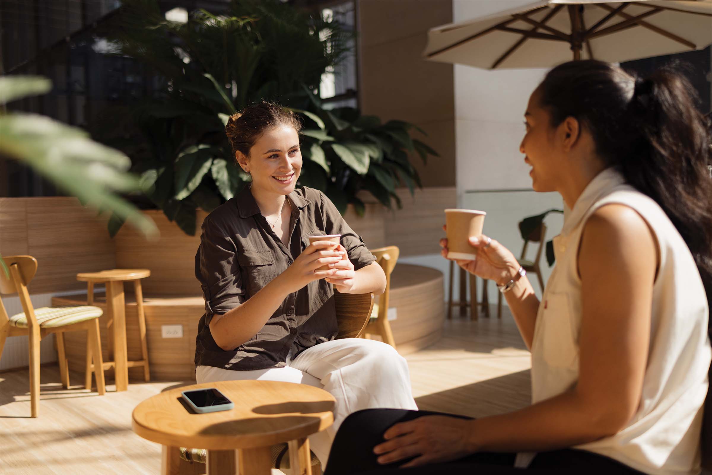 Two women chat over a cup of coffee.